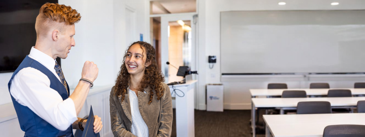 Graduate Student talking with a faculty member in an LMU classroom.